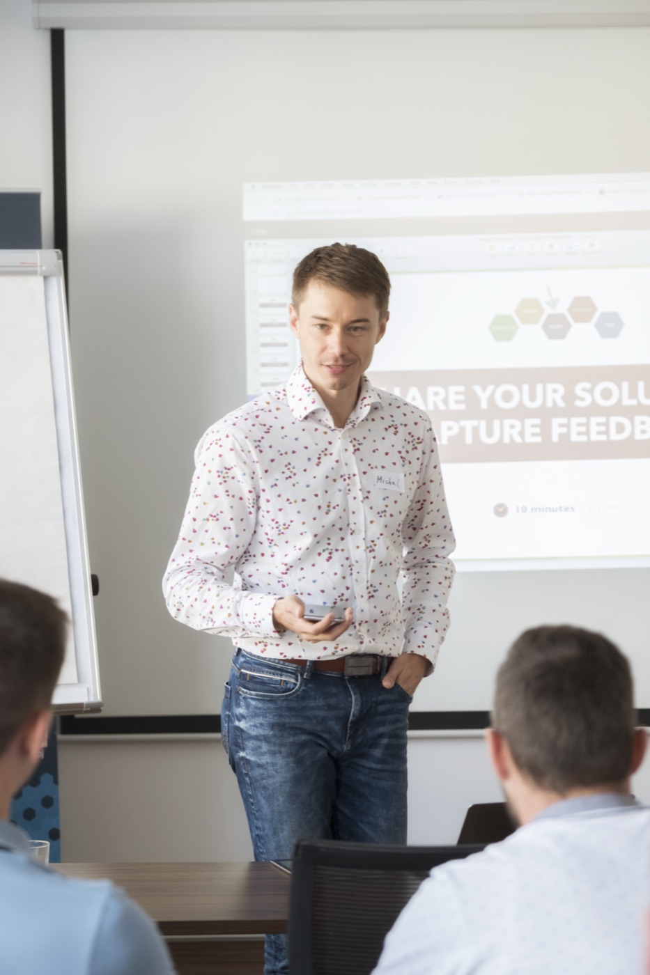 Michal Juhas presenting in front of a projected slide (2018)